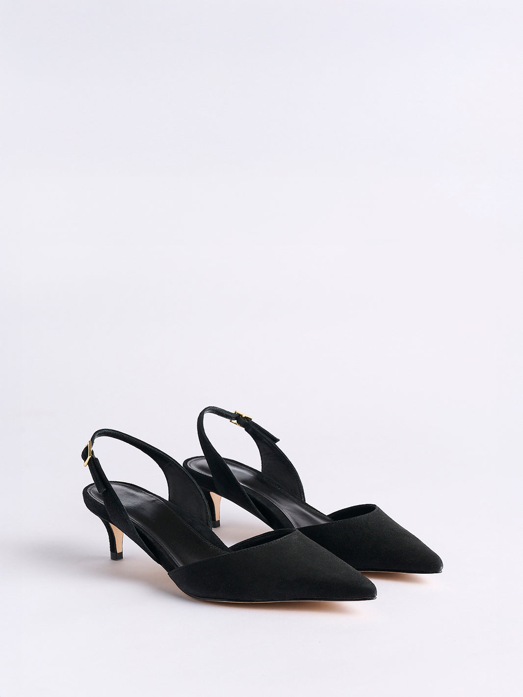 Angle view of a pair of black suede slingback kitten heels with a pointed toe.