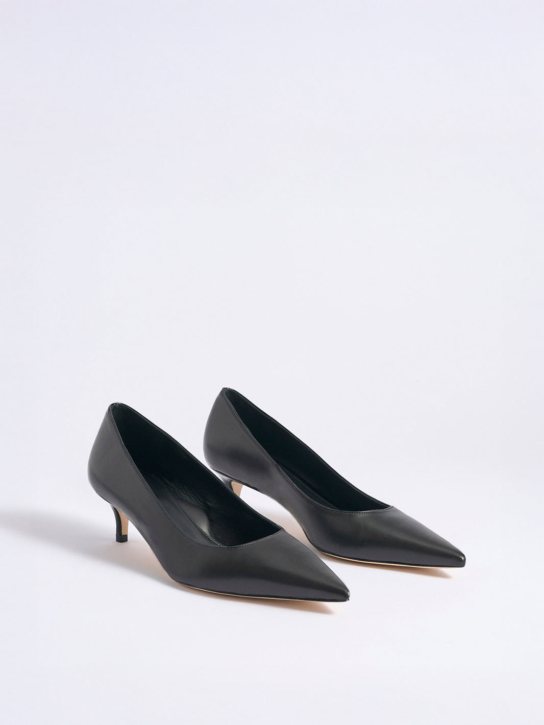 Angle view of a pair of black nappa leather kitten stiletto heel pumps with a pointed toe.