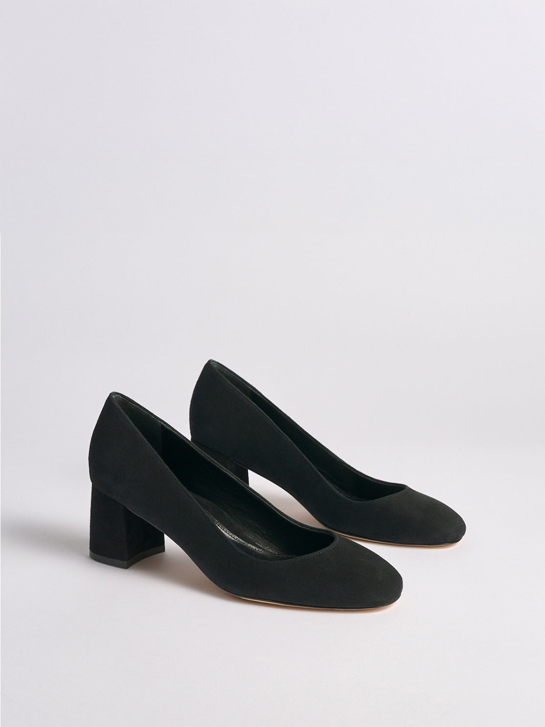 Angle view of a pair of black suede block heel pumps with a rounded toe.
