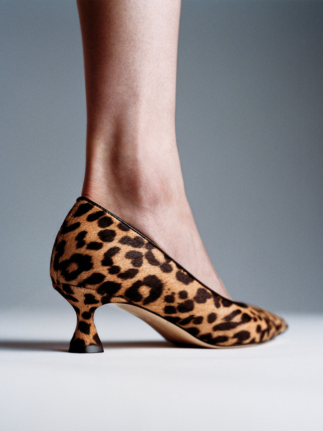 Angle view of a leopard hair calf flared kitten heel pump, shown on a model.