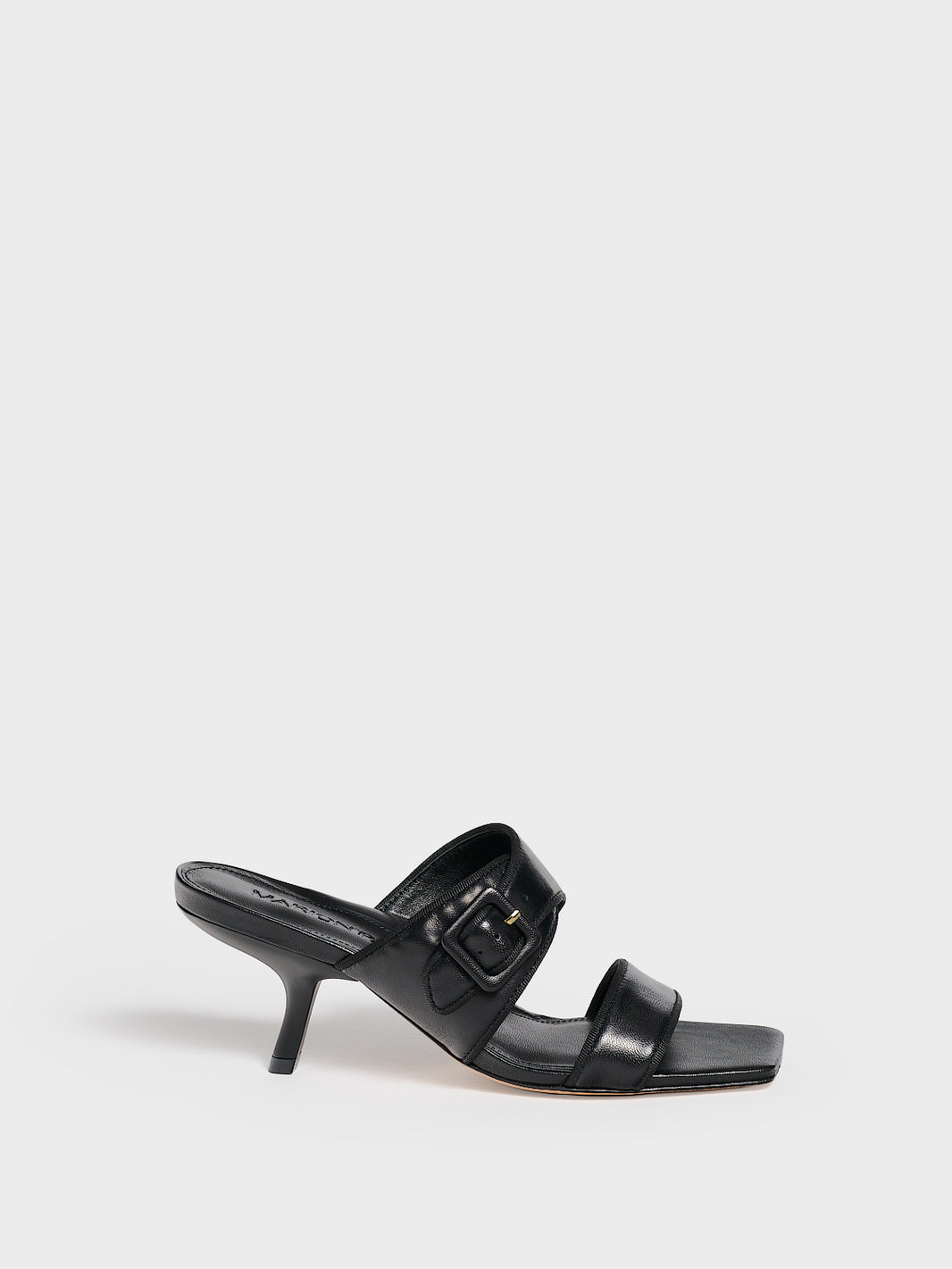 Profile view of a black leather slide kitten heel sandal with a buckle detail.