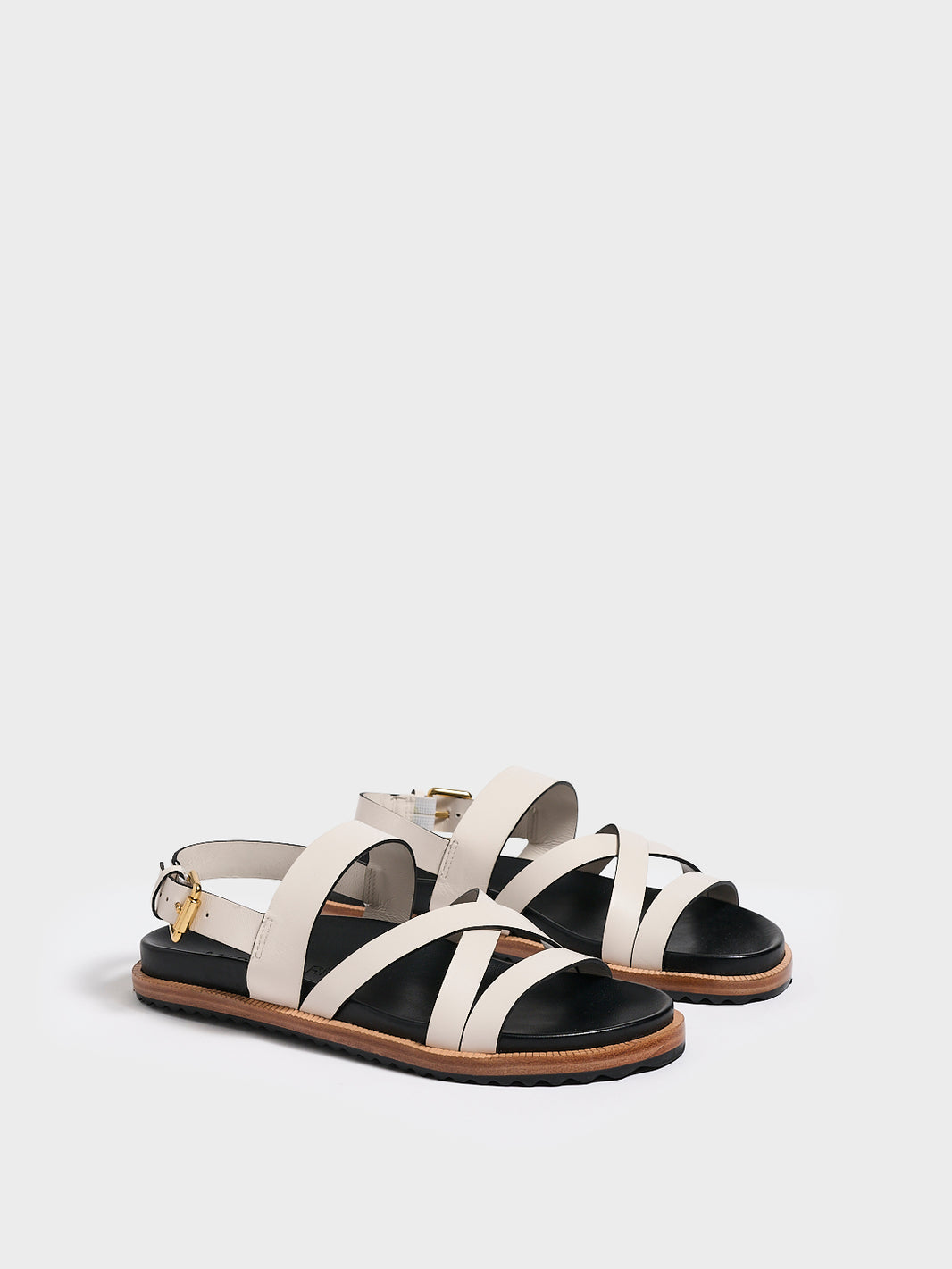 Angle view of a pair of ivory leather molded footbed slide sandals with an adjustable back strap.