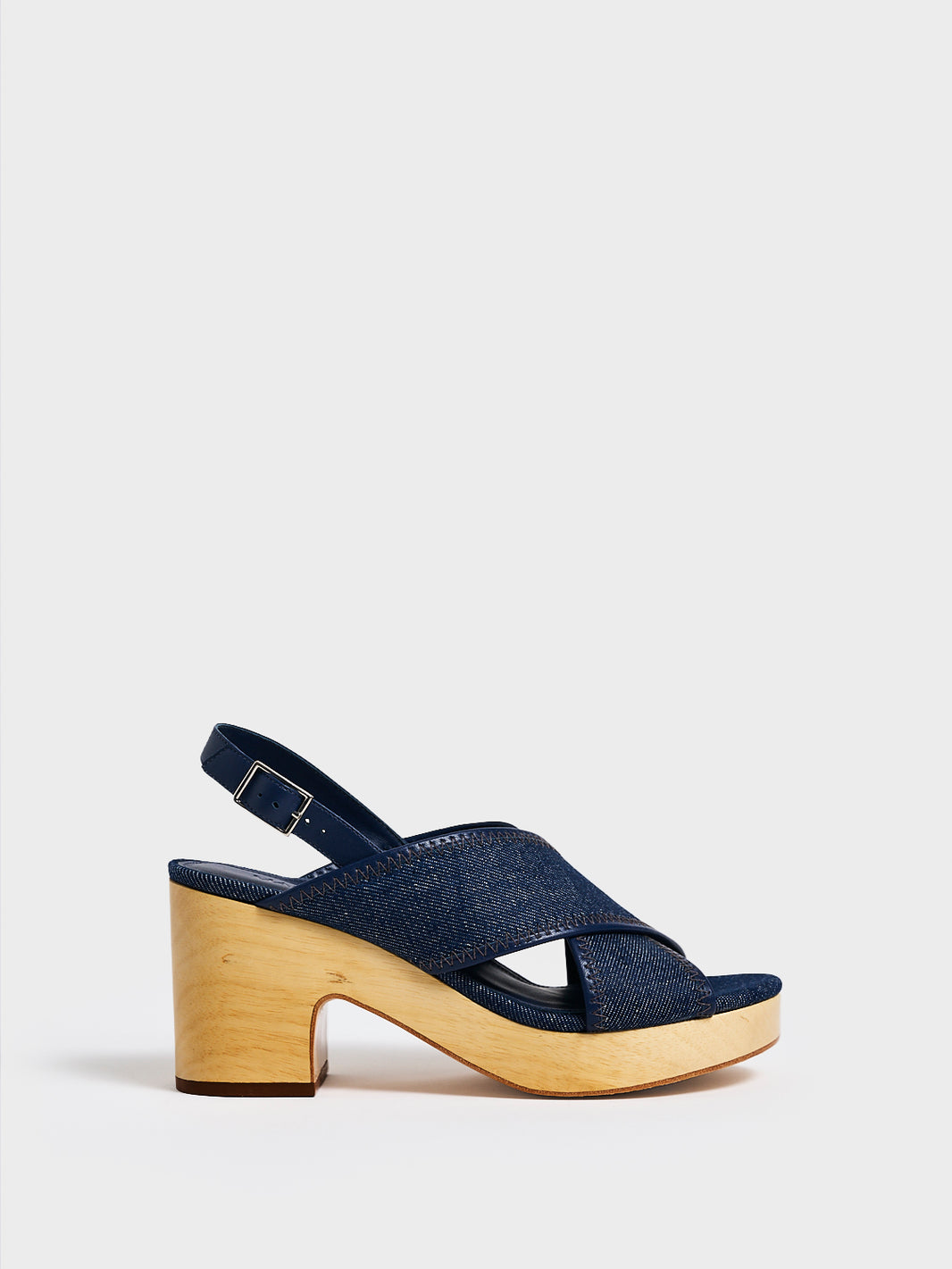 Profile view of a navy denim platform sandal with an adjustable back strap.
