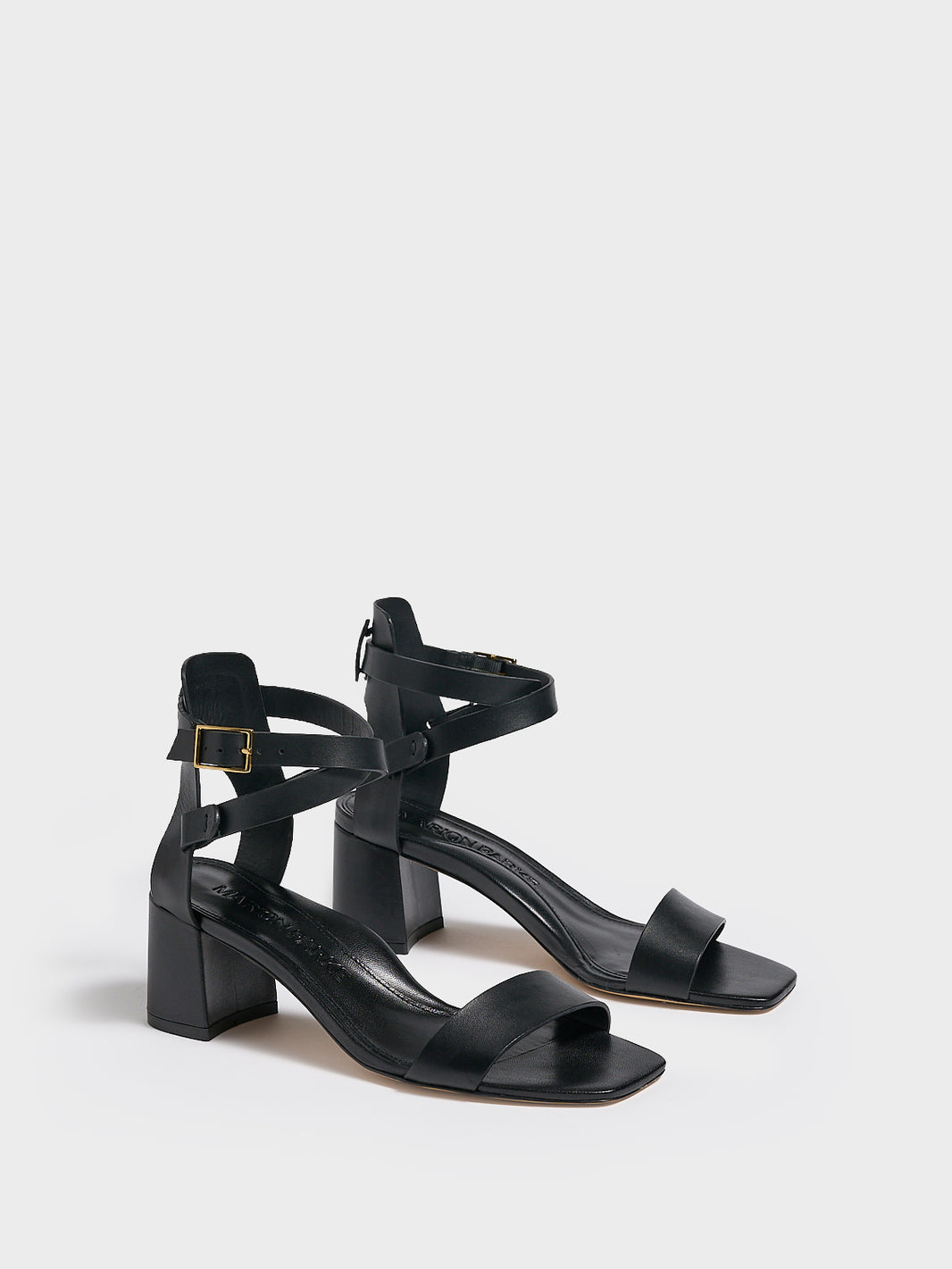 Angle View of a pair of black leather block heel sandals with an adjustable ankle strap design.