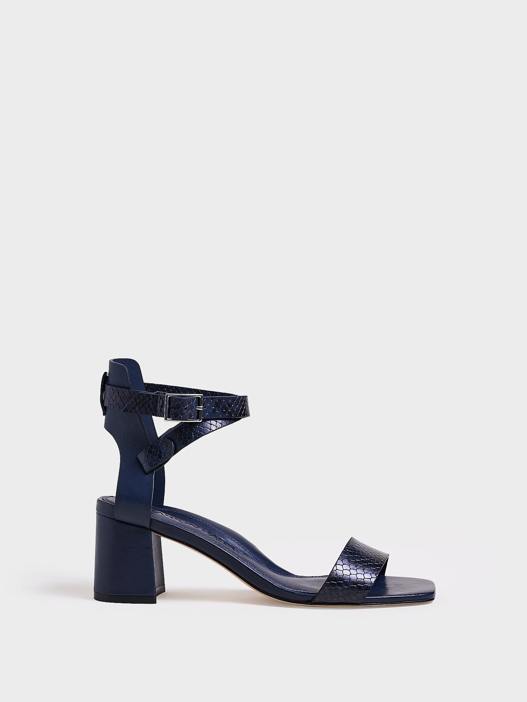 Profile view of a navy python leather block heel sandal with an adjustable ankle strap design.