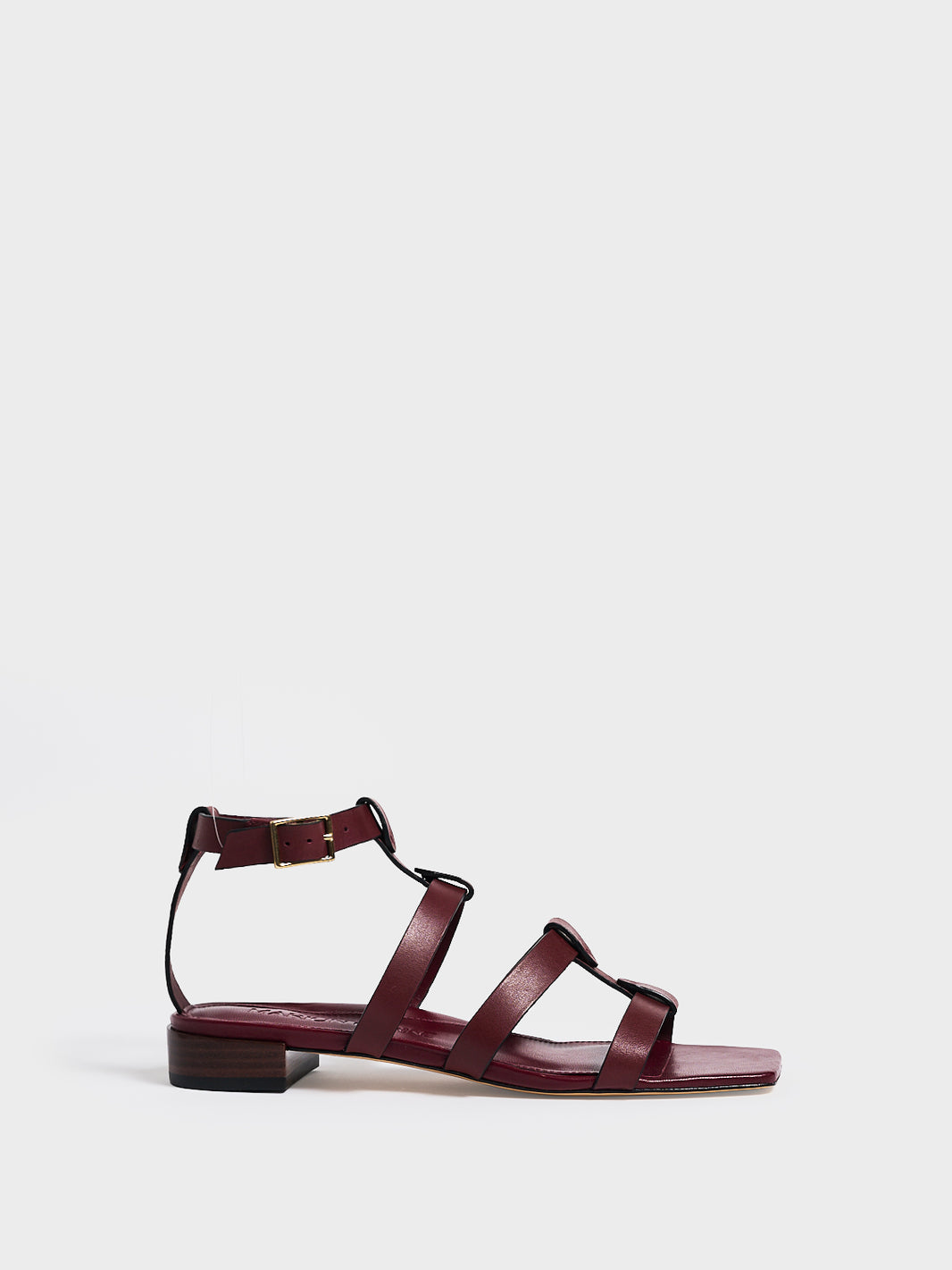 Profile view of an burgundy leather gladiator sandal with an adjustable ankle strap.