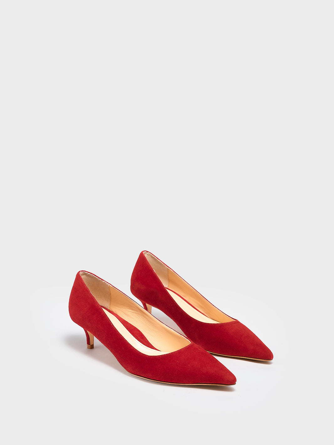 Angle view of a pair of red suede kitten stiletto heel pumps with a pointed toe.
